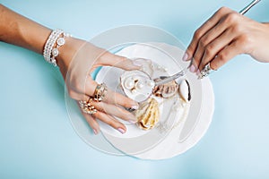 Beautiful woman hands with pink manicure holding plate with pearls and sea shells, luxury jewelry concept