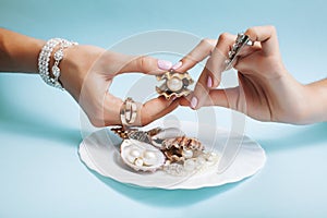 Beautiful woman hands with pink manicure holding plate with pearls and sea shells, luxury jewelry concept