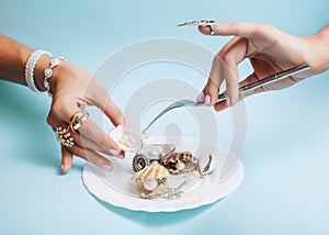 Beautiful woman hands with pink manicure holding plate with pearls and sea shells, luxury jewelry concept