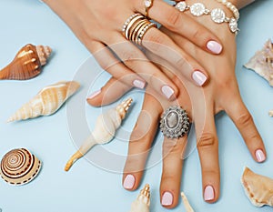 beautiful woman hands with pink manicure holding plate with pearls and sea shells, luxury jewelry concept