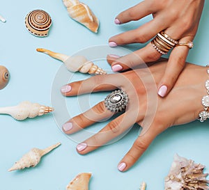 beautiful woman hands with pink manicure holding plate with pearls and sea shells, luxury jewelry concept