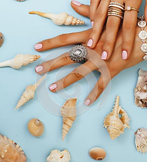 beautiful woman hands with pink manicure holding plate with pearls and sea shells, luxury jewelry concept