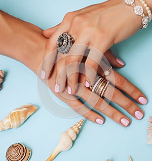 beautiful woman hands with pink manicure holding plate with pearls and sea shells, luxury jewelry concept