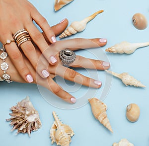 beautiful woman hands with pink manicure holding plate with pearls and sea shells, luxury jewelry concept