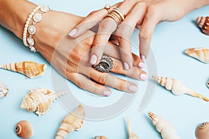 Beautiful woman hands with pink manicure holding plate with pearls and sea shells, luxury jewelry concept