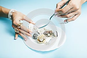 Beautiful woman hands with pink manicure holding plate with pearls and sea shells, luxury jewelry concept close up