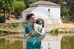 beautiful woman and handsome man latinos dancing bachata are dancing by the river in the forest. The couple do different postures