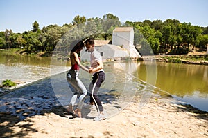 beautiful woman and handsome man latinos dancing bachata are dancing by the river in the forest. The couple do different postures