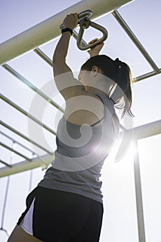 Beautiful woman hanging on bar at outdoor training spot or street workout in Barcelona beach & x28;SPAIN