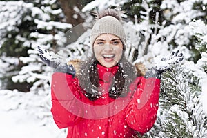 Beautiful woman is happy while is snowing in the park.