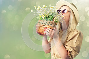 Beautiful woman in hat and with a basket of field daisies in sunny summer day.