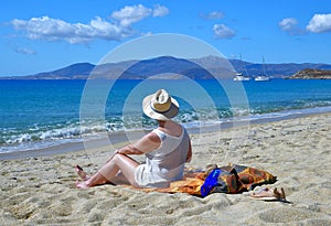 Beautiful woman in a hat enjoys the view of the beach of Naxos island in Greece.