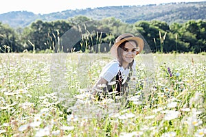 beautiful woman in a hat in a field of chamomile flowers