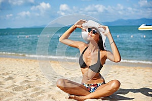 Beautiful woman in hat and sunglasses enjoing summer on a beach photo
