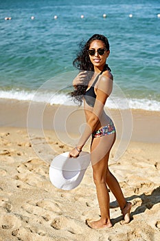 Beautiful woman in hat and sunglasses enjoing summer on a beach photo