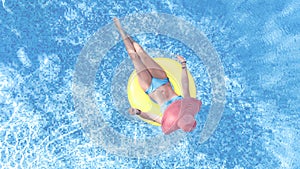 Beautiful woman in hat in swimming pool aerial top view from above, young girl in bikini relaxes swims on inflatable ring donut