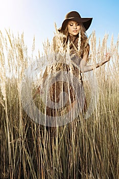 Beautiful woman in hat in a tallgrass meadow at golden hour photo