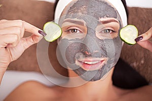 Beautiful woman having clay facial mask apply by beautician.