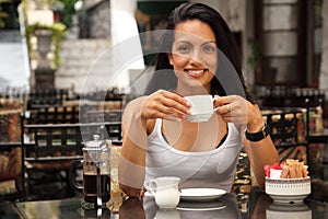 Beautiful woman having coffee in courtyard cafe