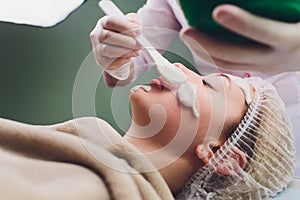 Beautiful woman having a facial cosmetic scrub treatment from professional dermatologist at wellness spa. Anti-aging