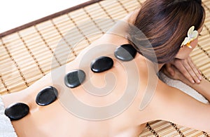 Beautiful woman having hot stones on her back in spa salon