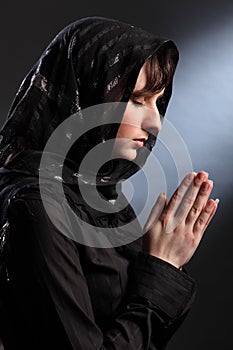 Beautiful woman in headscarf praying eyes closed