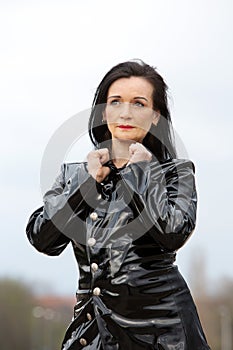Beautiful woman in her 50s standing outside with black latex coat