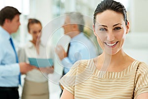 Beautiful woman with her business team at the back. Beautiful young woman smiling with her business team at the