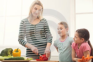 Beautiful woman with her daughters cooking salad photo