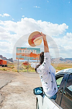 Beautiful woman on her trip by the car. Welcome to Utah road sign. Large welcome sign greets travels in Monument Valley