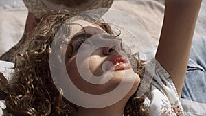 Beautiful woman hiding face from sunlight by hand close up. Portrait curly girl.