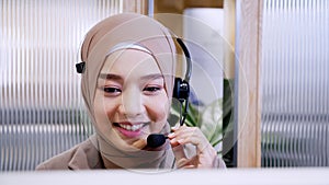 Beautiful woman in hijab at the computer with headset, distant work, call center.