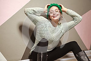 Beautiful woman in hipster stile clothes sitting on wooden floor