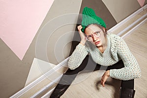 Beautiful woman in hipster stile clothes sitting on wooden floor