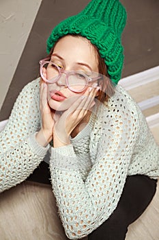 Beautiful woman in hipster stile clothes sitting on wooden floor