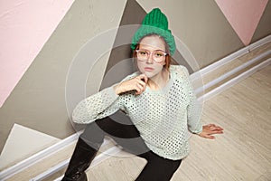 Beautiful woman in hipster stile clothes sitting on wooden floor