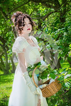 Beautiful woman in an historical bride dress with a wicker basket in her hands