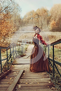 Beautiful woman in a historical dress descends a wooden staircase.