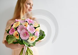 Beautiful woman hold bouquet of gerbera flowers pink and yellow happy smiling on grey