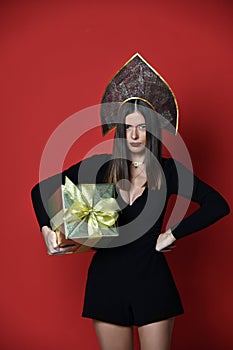 Beautiful woman hold gold present gift box in Russian traditional black kokoshnik hat angry photo