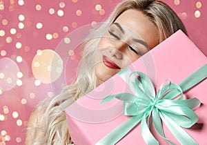 Beautiful woman hold pink Christmas presents gift box for new year celebration smiling dreaming