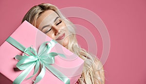 Beautiful woman hold pink and pastel green Christmas presents gift box for new year celebration smiling on pink