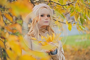 Beautiful woman holding autumn yellow leaves outdoors on fall nature background