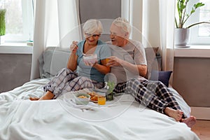 Beautiful woman holding bowl with cereals while spouse hugging her