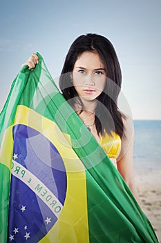 Beautiful woman holding a Brazil flag on beach
