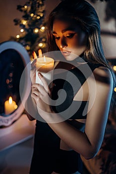 Beautiful woman holding a burning candle in her hands.