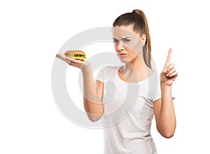 Beautiful woman holding a cheeseburger, saying NO to unhealthy food