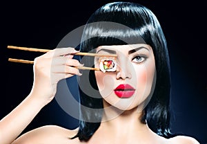 Beautiful woman holding chopsticks with sushi roll