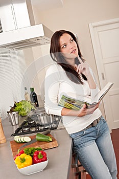 Beautiful woman holding cookbook in the kitchen
