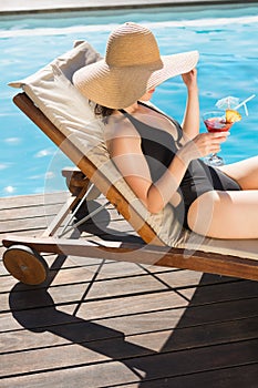 Beautiful woman holding drink by swimming pool